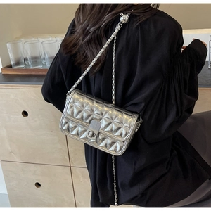 Close-up of silver quilted crossbody bag featuring chain strap and metallic twist lock