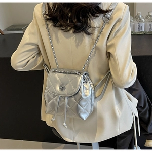 Detail of silver quilted leather mini backpack with chain strap on a model
