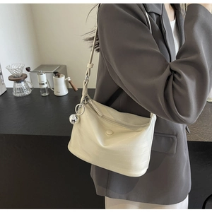 Detail of off-white crossbody bag with crocodile texture and silver metal ball charm
