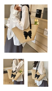 Detail of hand-woven straw tote bag featuring a 3D black leather bow and long straps