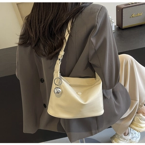 Detail of beige crocodile embossed shoulder bag with decorative silver ball pendant