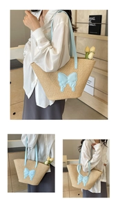 Detail of straw woven tote bag featuring light blue butterfly patch and matching straps