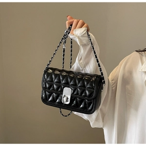 Detail of black quilted leather handbag with silver twist lock and chain strap