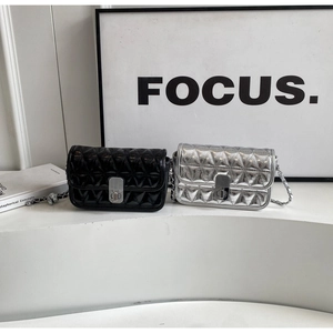 Macro shot of quilted chain bags in black and silver finishes on a white platform