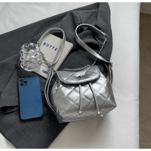 Close-up of silver quilted backpack with metallic chain strap and drawstring closure