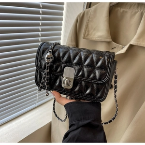 Close-up of black quilted shoulder bag with silver chain and vintage lock detail