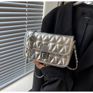 Close-up of silver quilted chain bag with metallic finish and metal turn-lock closure
