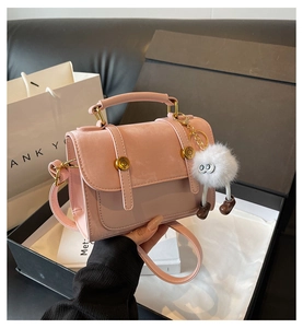 Detailed view of pink PU leather handbag with gold clasp and furry monster pendant in gift box