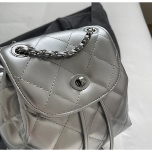 Detailed close-up of quilted silver backpack with metallic chain and twist-lock closure