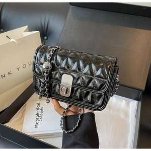 Macro detail of black quilted shoulder bag with silver clasp and metal ball ornament