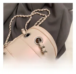 Close-up of pink pearlescent leather bucket bag featuring silver eyelets and chain strap