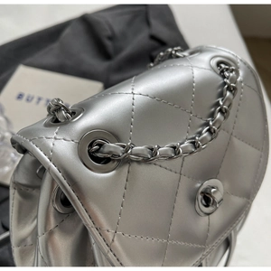 Detailed close-up of silver quilted texture and metallic chain strap on a small flap bag