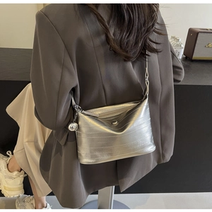 Detail view of silver metallic shoulder bag with pleated texture and metal ball charm