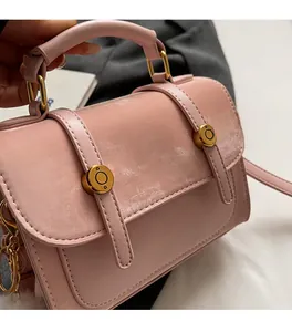 Detail of pink faux leather handbag showing golden metal buckles and smooth texture