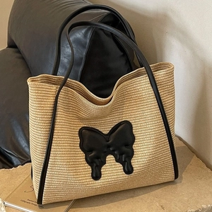 Straw tote bag with large black leather butterfly detail and long shoulder straps