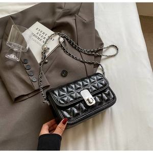 Close-up of quilted leather flap bag with silver twist lock and ball chain adjustment