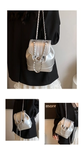 Close-up of bright silver metallic bucket backpack with chain strap and flap lock