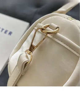 Close-up of white Boston bag featuring high-quality gold metal hardware and leather texture