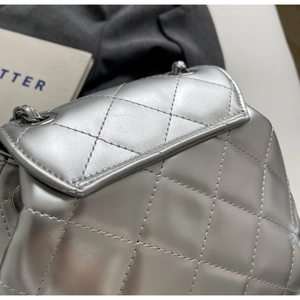 Macro shot of silver quilted leather texture and metallic chain strap on a flap bag