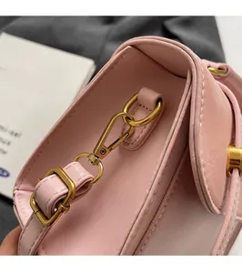Detail of glossy gold metal hooks and adjustable strap buckle on a pink PU leather bag