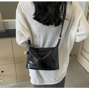 Detail of black glossy square bag with horizontal embossing and silver ball charm