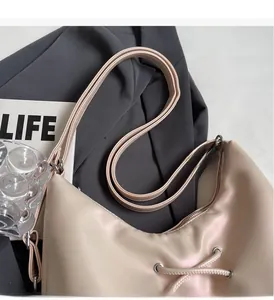 Detail of minimalist beige tote bag with shoulder strap and side drawstring on grey suit fabric