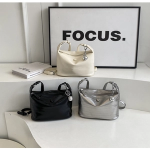 Detailed close-up of textured leather crossbody bags in cream, black, and silver colors