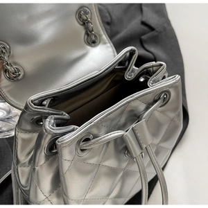 Macro detail of silver quilted backpack featuring drawstring closure and chain strap