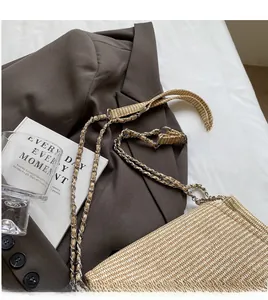 Detail of a beige straw shoulder bag showing the metal chain and woven strap texture