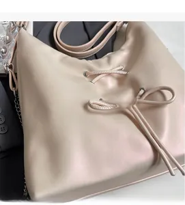 Detail of beige tote bag showing soft matte texture and decorative drawstring bow