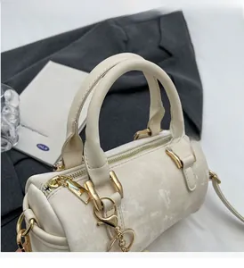 Detail of cream Boston bag featuring sturdy round handles and gold-tone metal hardware