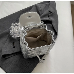 Detail of silver quilted backpack showing spacious khaki lining and drawstring closure