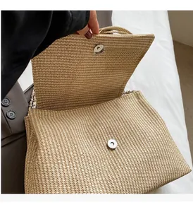 Detail of hand opening straw woven shoulder bag with silver magnetic snap closure