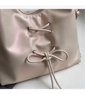 Detailed view of pearlescent tote bag featuring lace-up cross ties and bow details