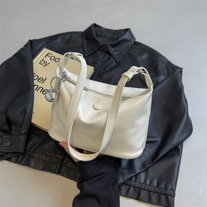 Detail of cream white patent leather handbag with wavy texture and silver ball charm