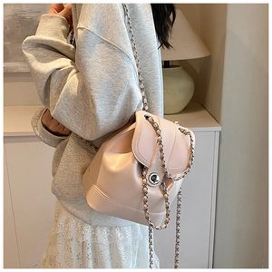 Chic beige leather bucket backpack with gold chain straps shown on a model