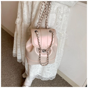 Detail showing the pearlescent pink chain backpack on a model wearing white lace dress