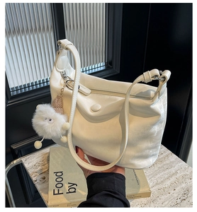 Detail of pearl white dumpling bag with soft leather texture and plush cartoon pendant