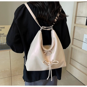 Detail of cream hobo bag featuring delicate bow ties and adjustable leather straps