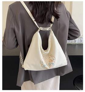 Detail shot of elegant floral embroidery on a minimalist cream white shoulder bag