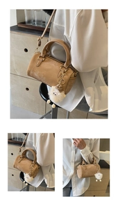 Detail of khaki Boston bag featuring a white plush sheep charm and metallic zipper