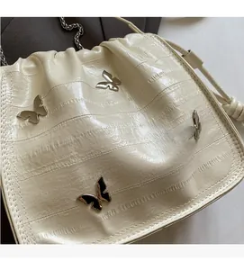 Close-up of cream-white cloud bag with silver butterfly charms and chain strap