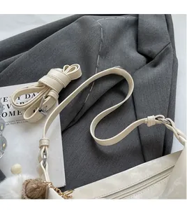 Detail of adjustable PU leather shoulder strap and white zipper on beige dumpling bag