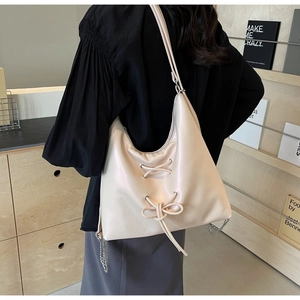 Detail of off-white PU leather tote with bow drawstring and stylish metal chain strap