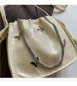 Detailed view of cream-white bag with crocodile texture and silver butterfly charms