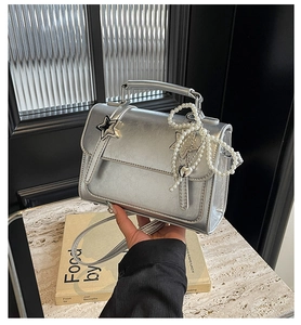 Détail du sac carré argenté métallisé avec décor d'étoile et breloque en perles
