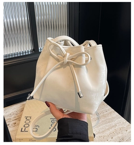 Détail du sac seau blanc avec nœud décoratif et embouts métalliques argentés sur cordon