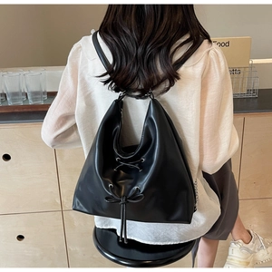 Close-up of black PU leather backpack with decorative drawstring bow on the back