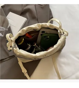 Detail of cream pleated shoulder bag interior showing high capacity for daily essentials