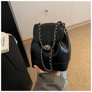 Close-up of black leather bucket backpack with silver chain strap and metal turn-lock